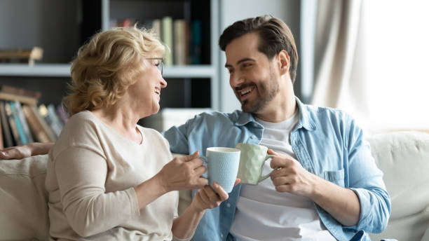 Adult son visit older mother drinking tea enjoy pleasant talk