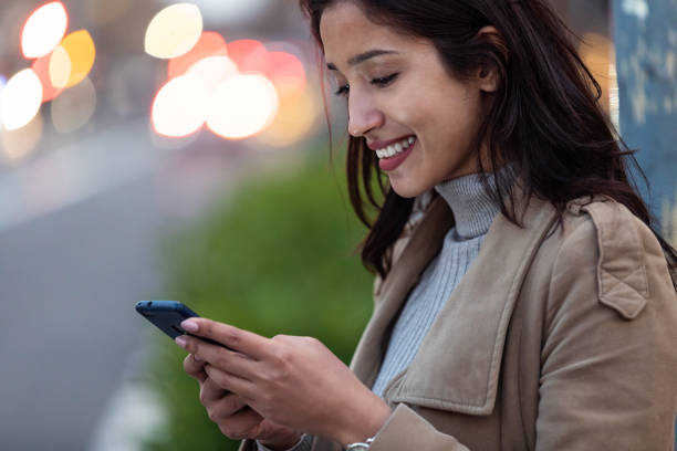 istock Pretty young woman using her smartphone while standing in the street. 1220791127