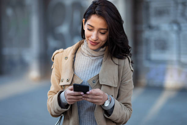 istock Pretty young woman using her smartphone while standing in the street. 1220791159