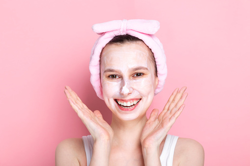 Young girl with cosmetic mask on her face and smiles wide