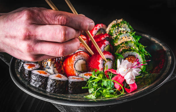 istock hand take sushi roll in plate on black wooden table background 1220795180