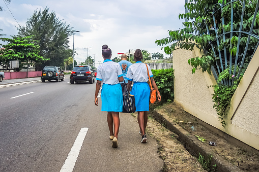 uniformed women walking on the road connecting the international airport with the African city of Libreville, capital of the Republic of Gabon