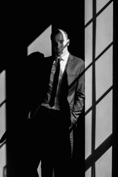 istock young man  dressed in a suit thinks standing against the wall in the company office 1220799305