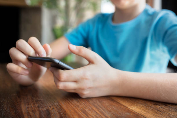 Mobile phone addiction young boy on cellphone Mobile phone addiction or cyber bullying young boy on cellphone online bullying stock pictures, royalty-free photos & images