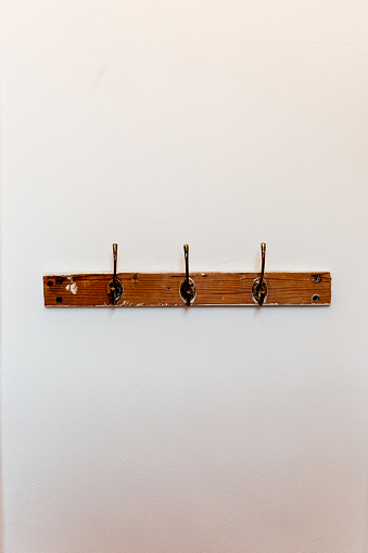 A portrait image of wooden coat hooks against a white wall