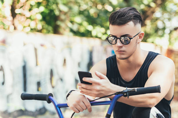 istock Man is using smart phone on bmx bicycle in park. close up 1220801663