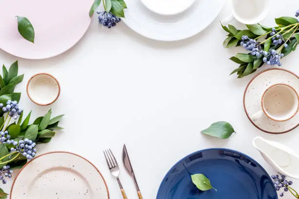 Photo of Plates and flowers frame for table setting on white background top view copyspace