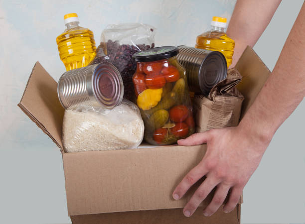 istock Volunteer hands hold food box for donation. Social, Help. Epidemic. Close-up. 1220802449