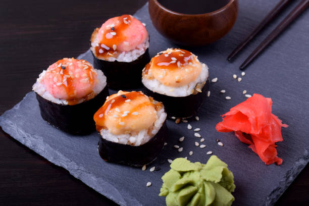 istock Sushi rolls assortment, wasabi, marinated ginger and soy sauce served on slate plate 1220806694