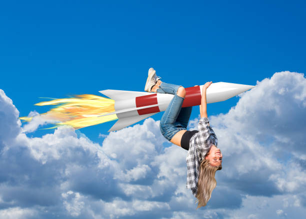istock Young woman hangs on a rocket and flies with it through the clouds 1220807540