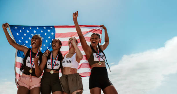 istock American female athletes celebrating a win holding flag 1220807750