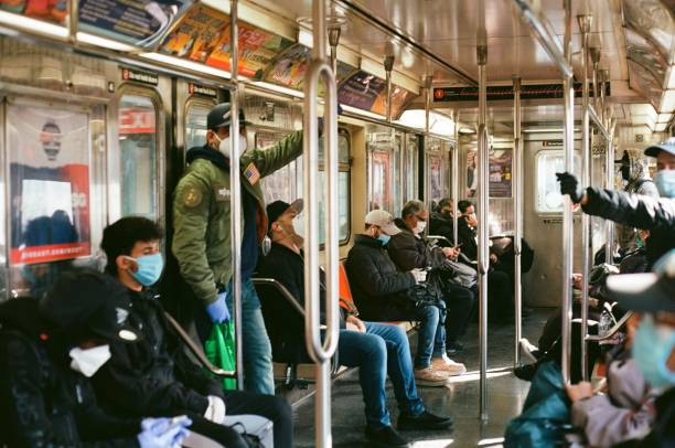 NYC commuters wear protective masks and gloves while riding the subway. NYC commuters wear protective masks and gloves while riding the downtown 1 Train subway. commuter train photos stock pictures, royalty-free photos & images