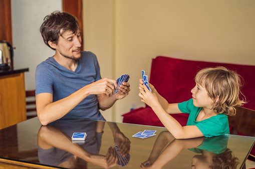 Father and son strategize and enjoy each other's company while playing board games on the living room floor