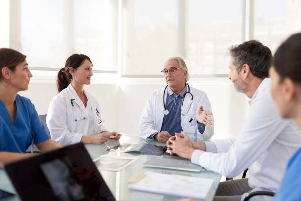 male senior doctor briefing his team and colleagues. - médico geral imagens e fotografias de stock