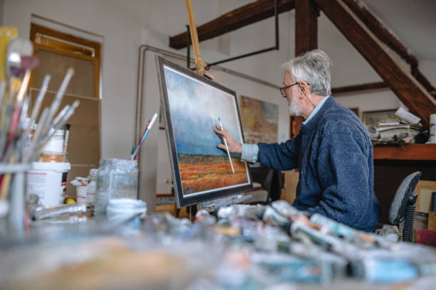 istock Professional painter fixing his painting with his finger 1220810821