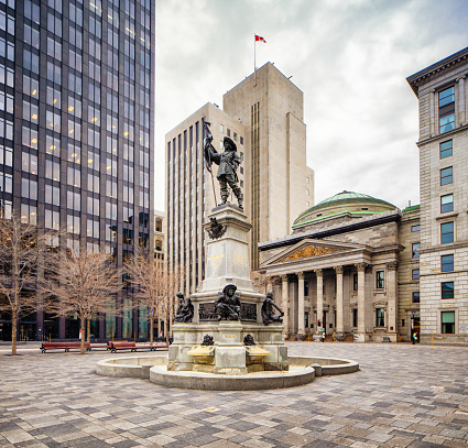 Montreal Place d'Armes with Maisonneuve Monument in the foreground, surrounded by office buildings photographed at Place d'armes. This monument was erected in 1895. Photographed during the 2020 Covid lockdown, explaining the absence of people and traffic.