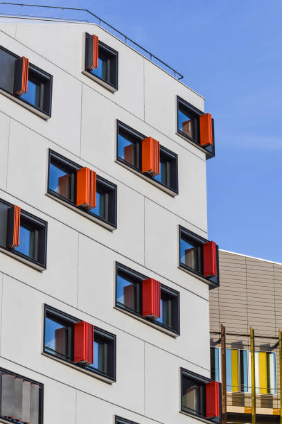 Detail of colorful windows in a modern architecture building. Windows shutters goes from red to orange and yellow and glasses reflects a blue sky. stock photo