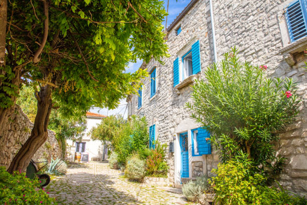 Exterior of an house with stone walls and blue shutters in windows in a street in an old town