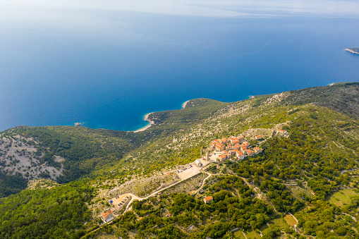 Aerial view of an idyllic landscape with roofs of houses in an old town on a hill visible near the coastline of Adriatic Sea,  Cres Island,  Croatia