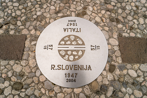 View from above of a metal circular sign marking the border between Slovenia and Italy against cobblestone street,  Nova Gorica,  Slovenian Littoral,  Slovenia