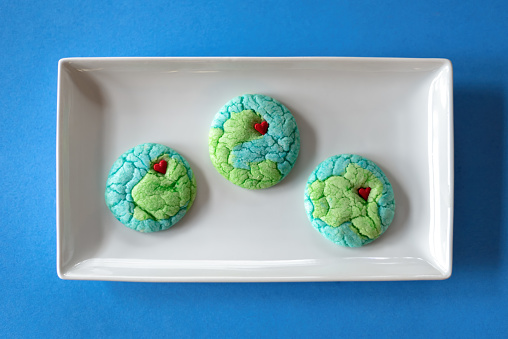 Plate of cookies shaped like planet earth on a blue background