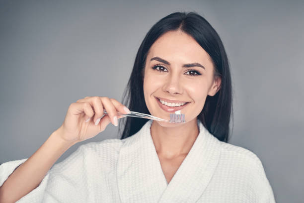 istock Happy Caucasian young female brushing her teeth 1220821620