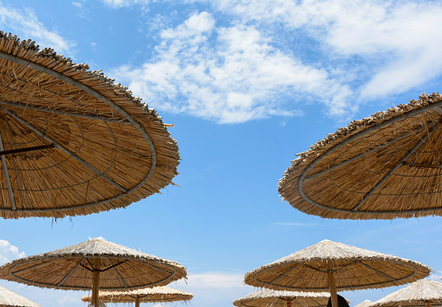 Wooden beach umbrella and cloudy sky in Greece