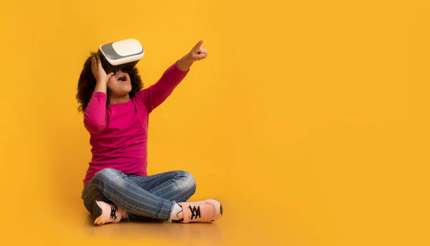 pequeña niña afro que usa auriculares vr, experimentando realidad virtual - child discovery surprise playing fotografías e imágenes de stock