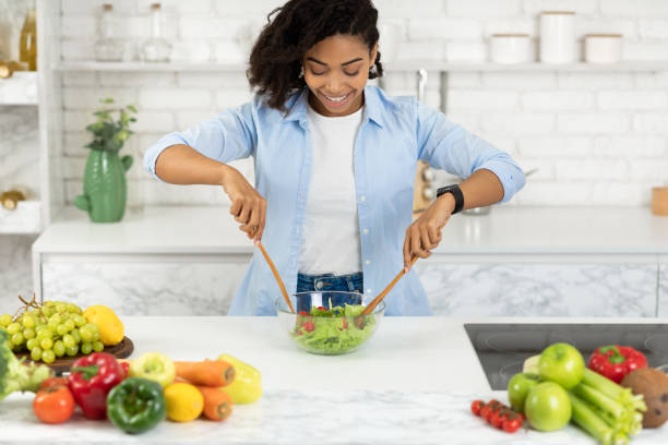 istock Beautiful young black girl preparing vegetable salad 1220825869