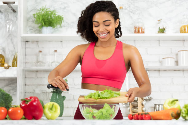 istock Beautiful young afro girl preparing vegetable salad 1220825934