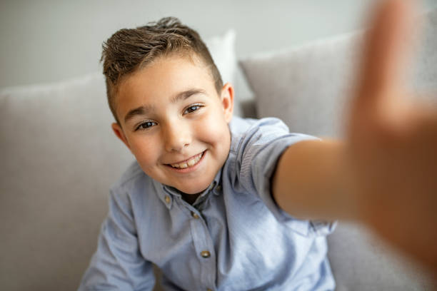 Smiling cute boy taking photos and facetime chatting.
