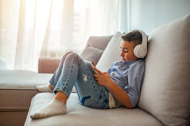 istock Little boy aged 6 listening to the music using modern tablet 1220827031