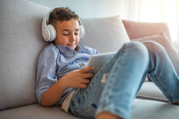istock Little boy in headphones is using a digital tablet and smiling 1220827052