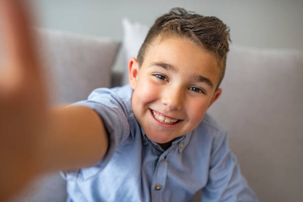 istock Cute little boy taking selfie on light background. 1220827187