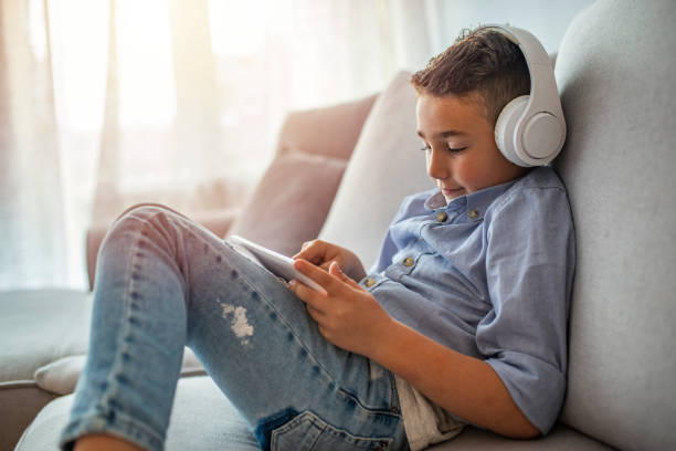 istock The 6 year old boy is wearing white headphones and is using tablet. 1220827220