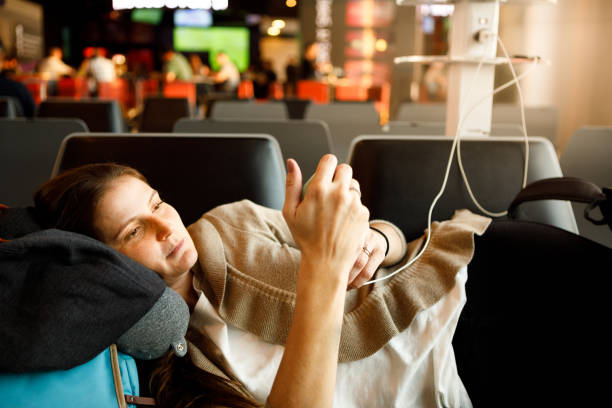 istock Beautiful woman lying and using smartphone at airport 1220827719