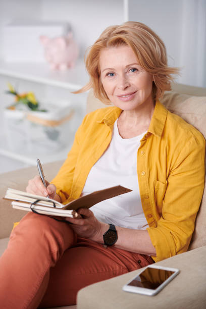 istock Successful businesswoman making working notes while sitting on couch at home 1220829764