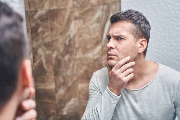 istock Man examining the skin on his face 1220830496