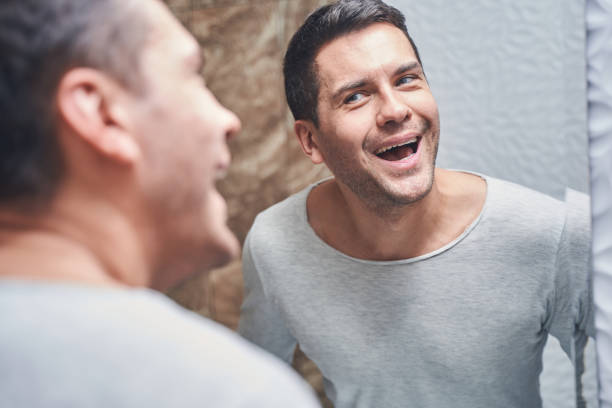 istock Man staring at his teeth in the mirror 1220830501
