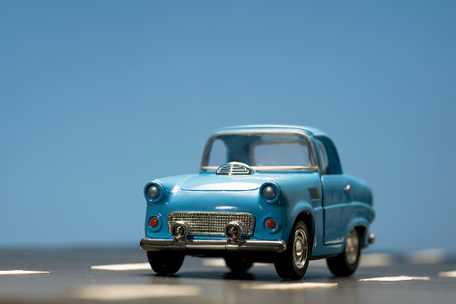 Front view of a blue toy car on on an asphalt road.
