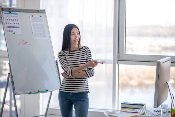 istock Dark-haired tutor in a striped shirt making presentation 1220834518
