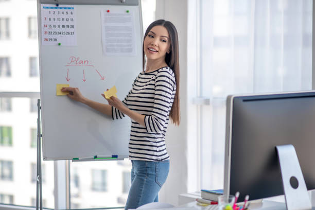 istock Dark-haired tutor in a striped shirt explaining new material 1220834531
