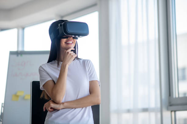 istock Dark-haired girl standing wearing vr headset and smiling 1220834562