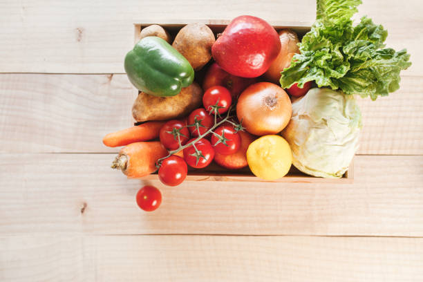 istock Fresh produce donation box on light wooden background. Fruit and vegetables delivery box. 1220836235