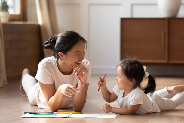 asiatische mutter und tochter liegen auf boden zeichnung mit bleistiften - playful mother playing daughter stock-fotos und bilder