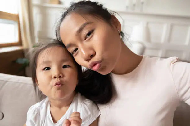 Photo of Beautiful mother little daughter taking selfie webcam faces view