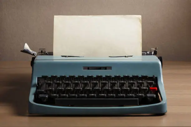 Photo of Vintage typewriter with blank paper sheet. Space for your text.