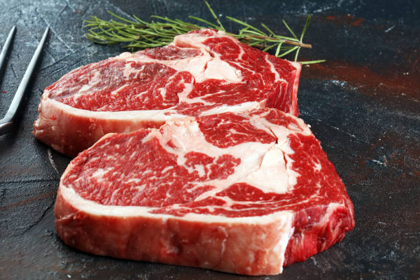 Steak. Two fresh raw rib-eye steak with rosmary in a rustic style table