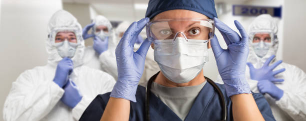 Team of Female and Male Doctors or Nurses Wearing Personal Protective Equiment In Hospital Hallway Team of Female and Male Doctors or Nurses Wearing Personal Protective Equiment In Hospital Hallway. guarding photos stock pictures, royalty-free photos & images