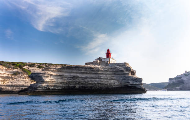 Ancient stone fortress perched on rugged cliff overlooking the sea with bright sun rays shining above. Coastal landmark with dramatic natural landscape and historic architecture. Scenic ocean view with old buildings.
